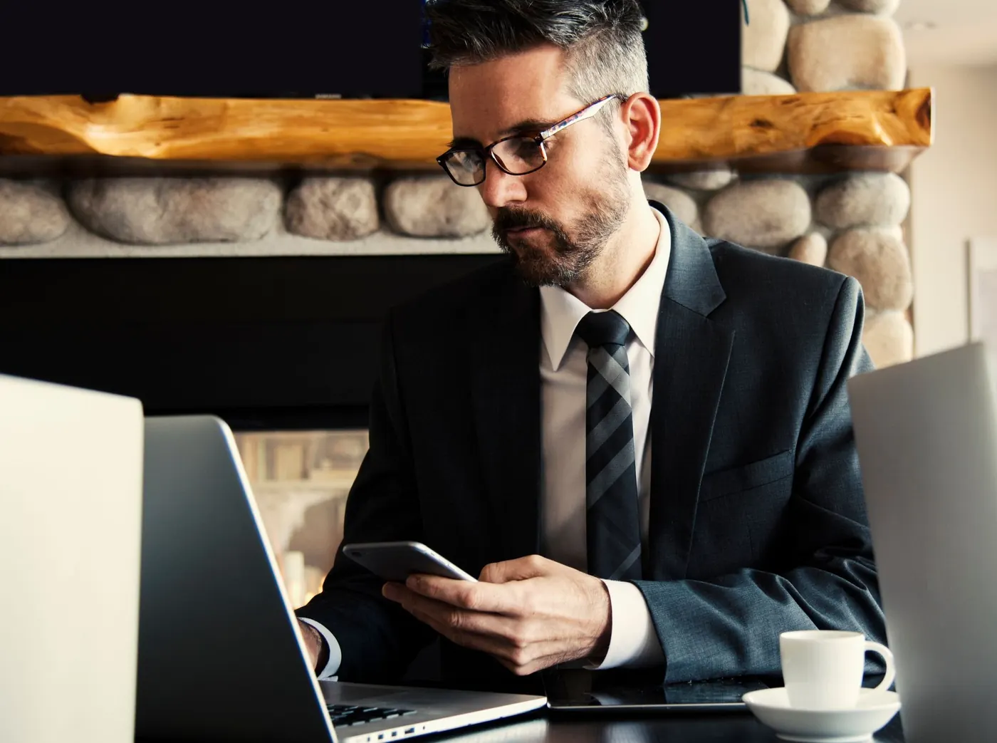 Attorney at his desk checking a phone next to his laptop